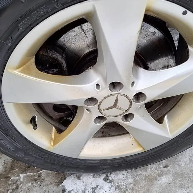 Skitten Mercedes-felg med synlige bremser og snø på bakken.